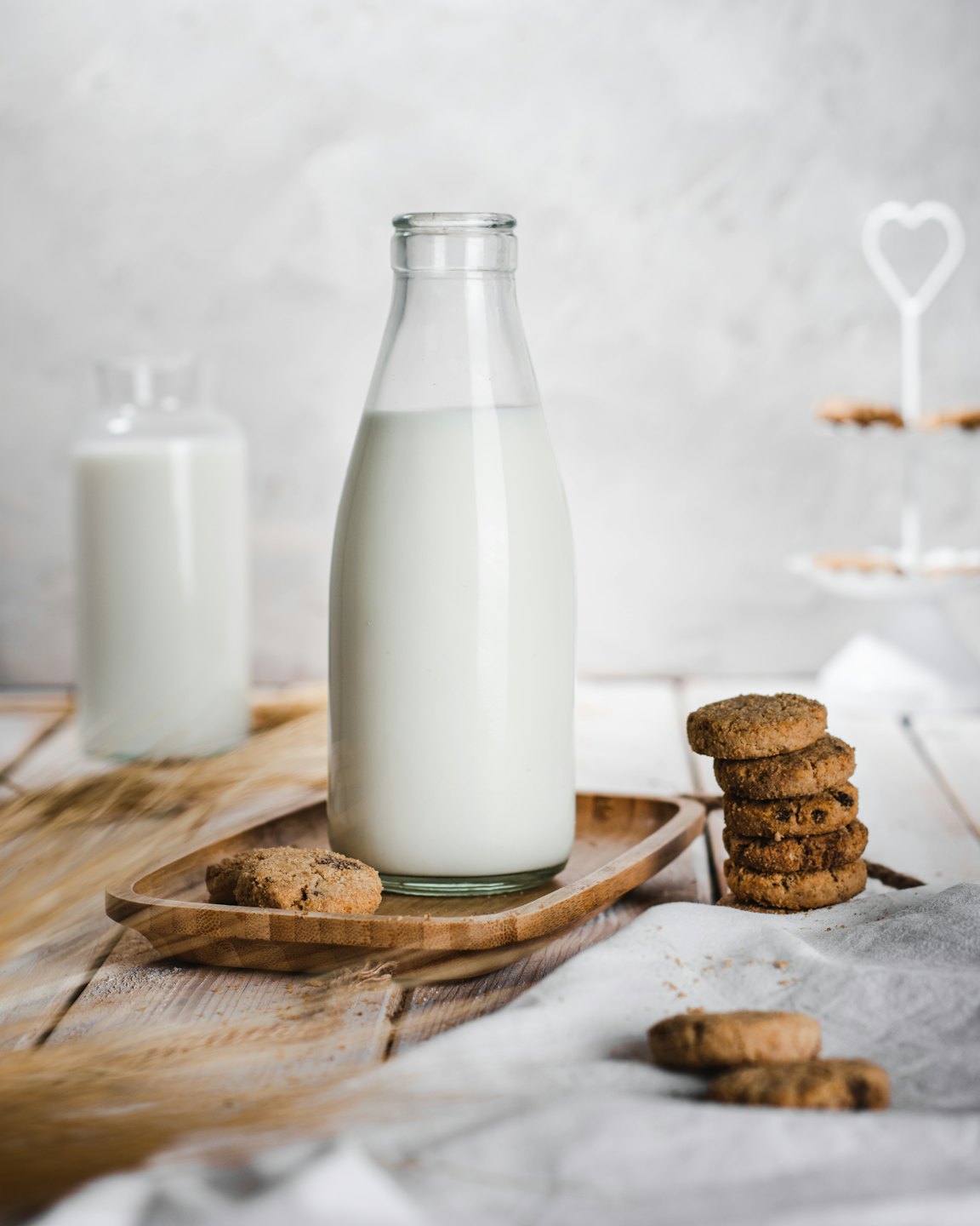 Due bottiglie di latte con biscotti su un vassoio di legno.